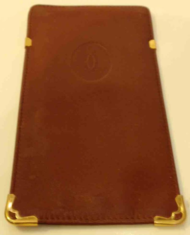 This is a thin burgundy leather eyeglass case with gold hardware at the corners by Cartier, from the 1980's. <br />
<br />
Measurements:<br />
Height: 6 1/4