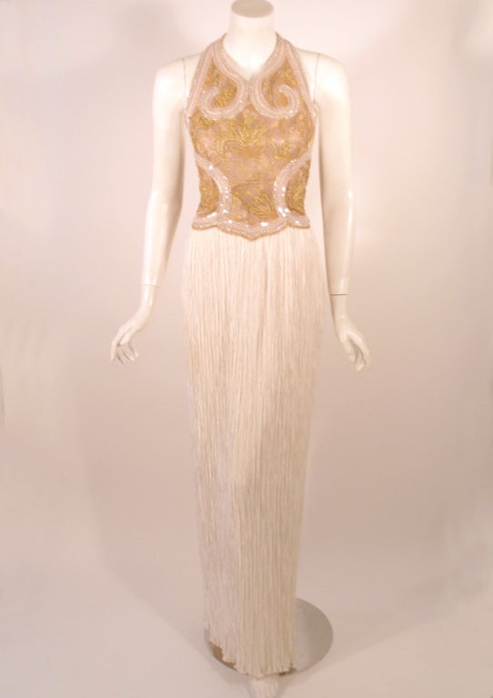 This is a lovely evening gown from Mary McFadden. It is made of her signature pleated poly fabric skirt, with a a gold tone and white beaded halter style bodice. There is a zipper at the side.

Size: 4 US

Measurements: 
Bust: 34