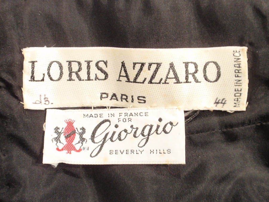 This is a beautiful evening gown made by Loris Azzaro, for Giorgio of Beverly Hills. It is made of black taffeta and sheer lace net with sequins cascading down the bodice and exaggerated sleeves. There is an underskirt that has the same sequin