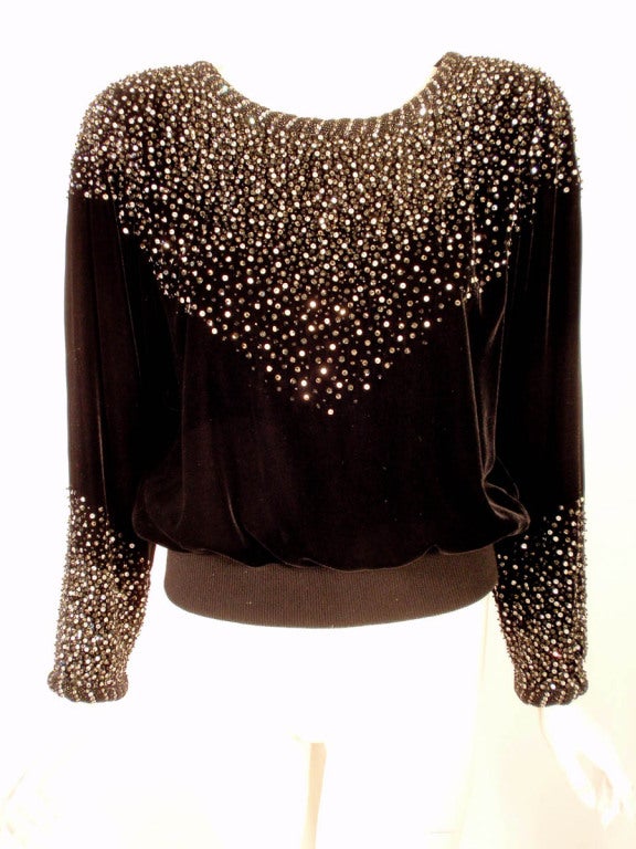 This is a lovely evening top from Valentino night. It is a blouson style made of black velvet with black and silver beads and sequins cascading from the shoulders. There is a rib knit hem, zippers at the cuffs, shoulder pads, and it is fully