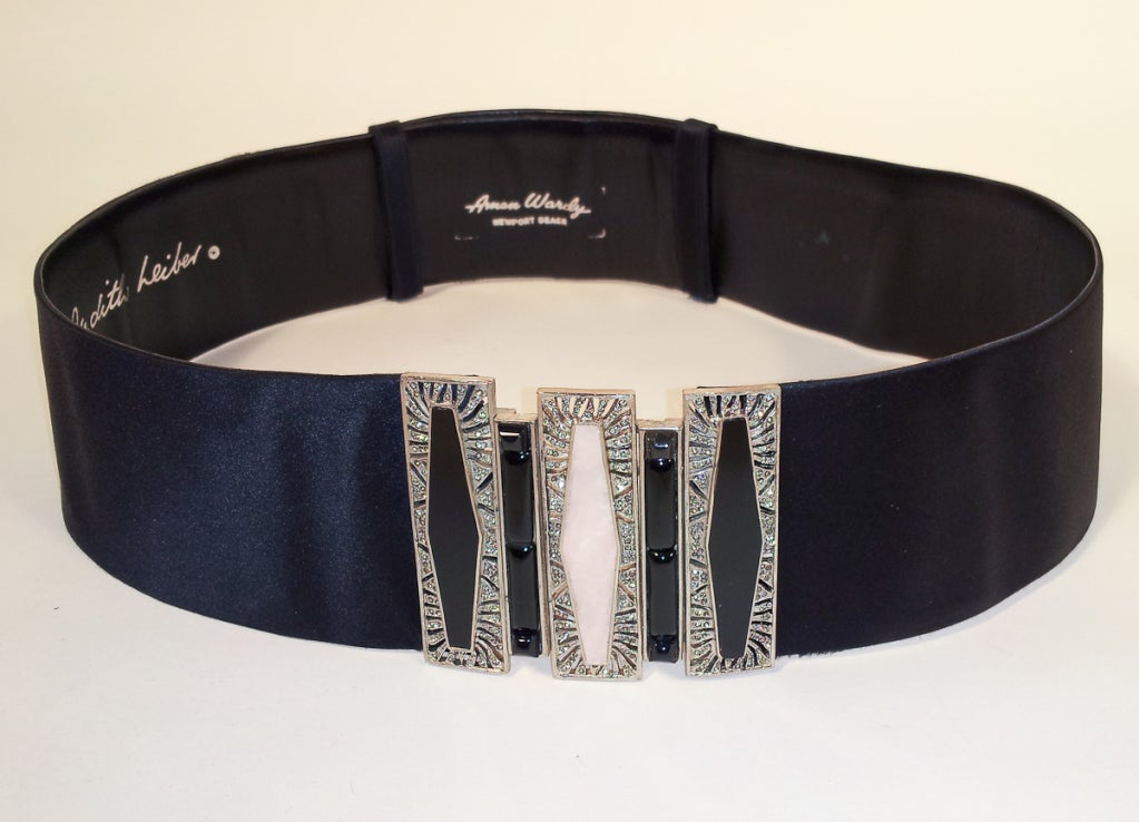 This a fabulous belt from Judith Leiber. It is made of a black silk satin with a silver tone metal buckle, accented with tones. It has a very Art Deco look to it. it was originally purchased at Amen Wardy, Newport Beach. It is