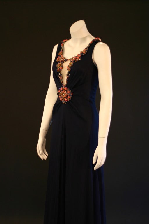 This Jenny Packham evening gown features a gorgeous compliment of midnight blue silk crepe with contrasting coral jewels. 

The gown is layered in silk crepe (top) and silk satin lining. It zips up the back, and has a fitted waist and a-line