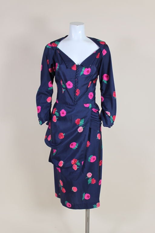 Fantastic 1950s Ceil Chapman dress is made from luxurious, navy blue silk printed with vibrant coral, fuschia and hot pink posies. Chapman's signature draping techniques are at work with an elegant side swag that leads into a bustle-type back.