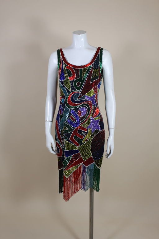 Fabulous 1980's cocktail dress from Oleg Cassini is fully embellished with multi-colored beads and sequins. Letters of the alphabet and geometric shapes are crafted from hand sewn glass bugle beads, mini pearls, iridescent sequins and seed beads in