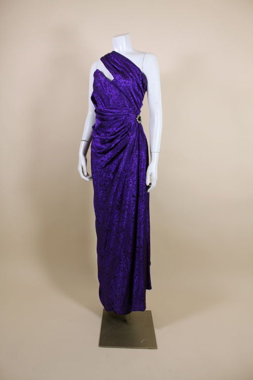 Glamorous, asymmetrical gown from Parisian designer Emanuel Ungaro takes its cues from a Grecian goddess gown with pleats and dramatic draping. Done in an amethyst purple silk jacquard, this lovely gown has radiating pleats from the waist accented