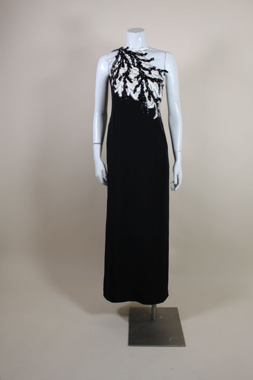 Elegant, chic asymmetrical gown from Bill Blass is made from black crepe with a single-shoulder bodice embellished with shiny black and white sequins sewn in a coral shaped motifs. Sequins are accented with glass beads and glittering crystals. Fully