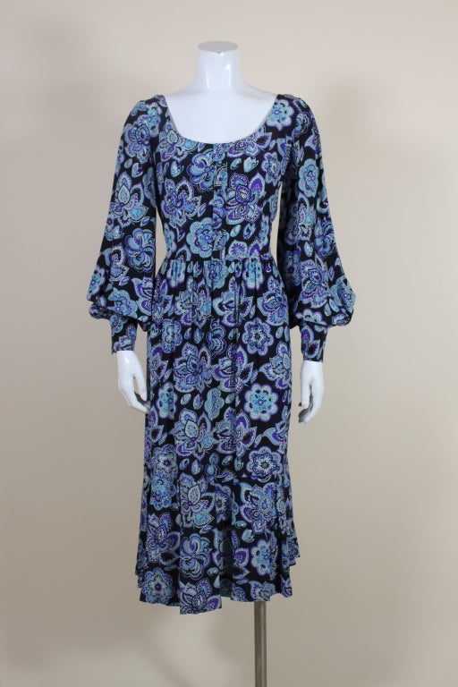 Lovely, 1970s-era silk Pucci dress features a festive, floral paisley motif in shades turquoise, sky blue, violet and white on a black ground. Long sleeve dress has a decorative placket detail with buttons down center front, blouson sleeves and a