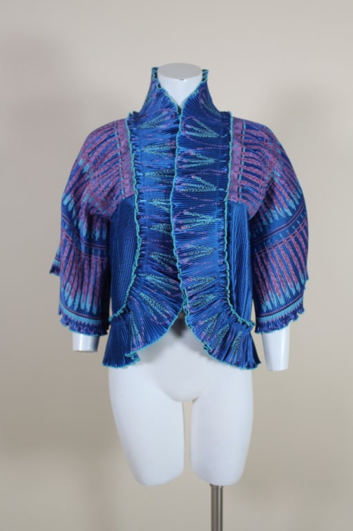 This gorgeous peacock blue Zandra Rhodes butterfly jacket features her signature micro accordion pleating and silk screen technique. Pink, red and turquoise paint is applied in rhythmic feather-like designs along the neckline and throughout the top