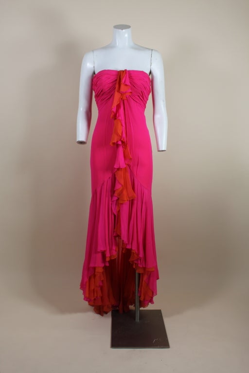 Gorgeous flamenco inspired evening gown from iconic designer, Bob Mackie is made from layers of hot pink and vivid orange silk chiffon. Gown is fitted through the body, with a pleated bust and a dramatically ruffled hem that cascades into a subtle