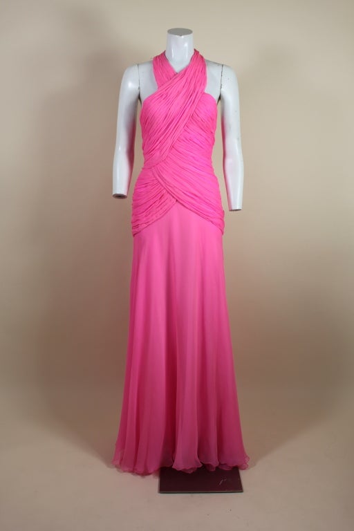 Absolutely fabulous 1980's Scaasi gown is crafted from delectable hot pink crepe chiffon. Halter bodice is body hugging with hand pleated panels that wrap around the figure. Skirt is cut on the bias and cascades into a subtle flair. Fully lined with