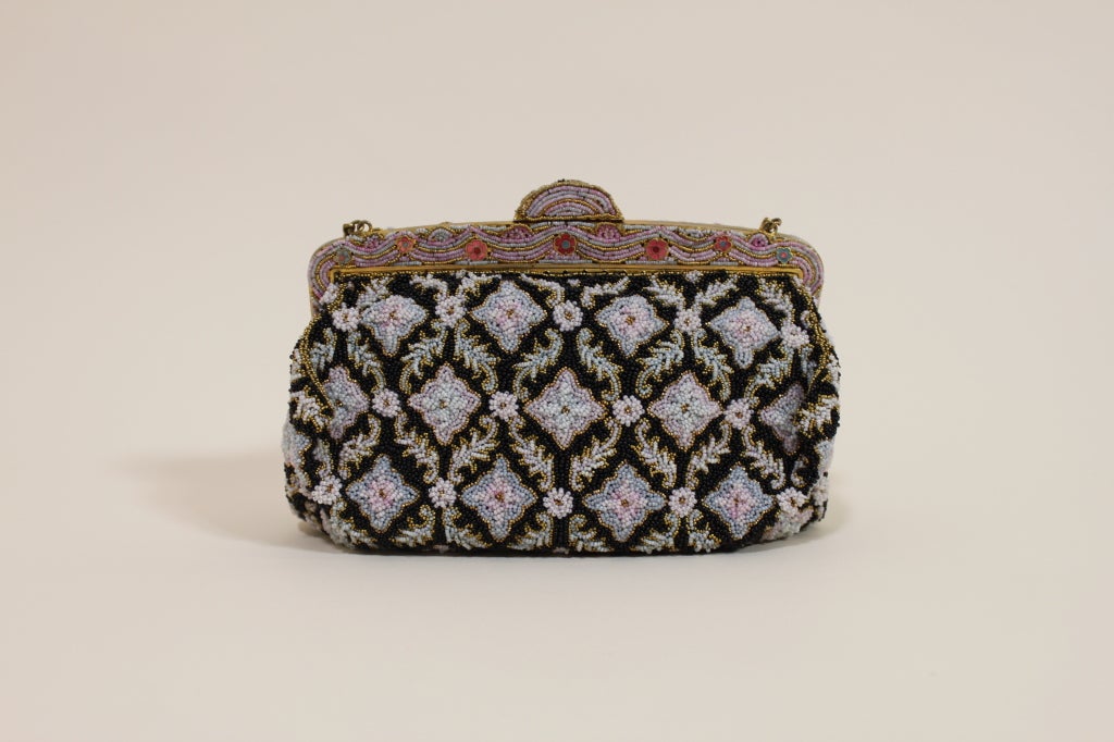 Lovely 1950s evening bag is beaded entirely with tiny glass beads in shades of black, luxe gold, pale blue, pale green and pale pink arranged in a diamond shaped floral motif. Beads are layered to build texture. Exquisite frame is beaded with pastel