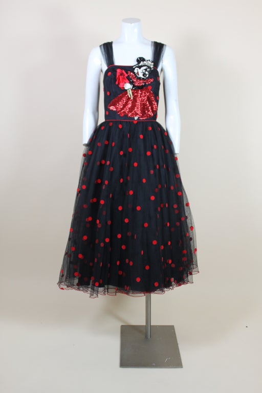 This whimsical 1980’s party dress features a fantastic appliquéd Minnie Mouse made entirely of iridescent sequins in graphic red, white, silver and black. Minnie is holding a silk flower bouquet as she bats her eyelashes at an unknown suitor! Dress