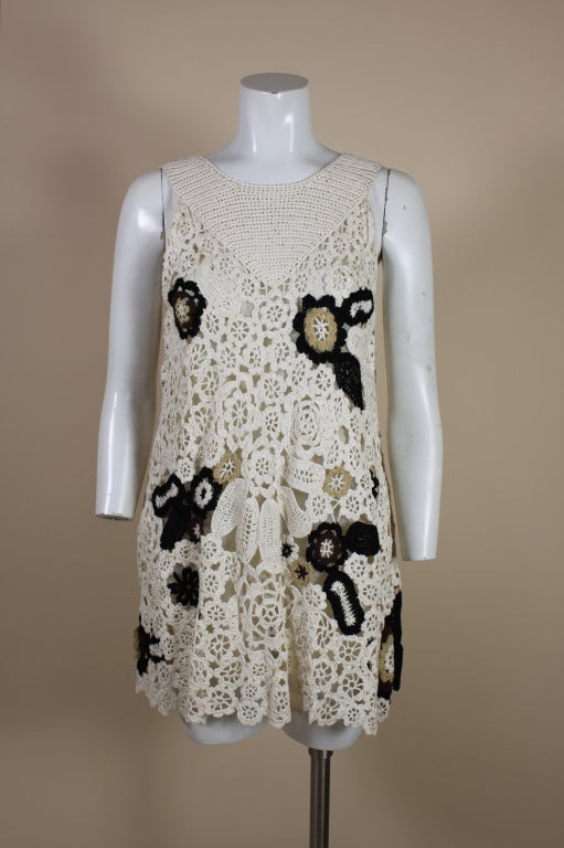 Adorable mini dress from Oscar de la Renta is made from cream crocheted silk in an asymmetrical floral pattern. The cream dress is punctuated by areas of boldly graphic black and brown flowers. Dress is lined in silk tulle. Tagged a size Medium.<br