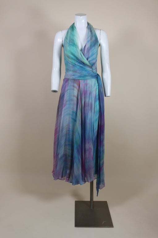 Breezy, sexy 1970’s halter dress is made from diaphanous silk chiffon tie dyed in watercolor ombré shades of aqua, teal, lavender, and violet. Blouson style bodice wraps around from the neck to the back and ties at the side. Fully lined in aqua