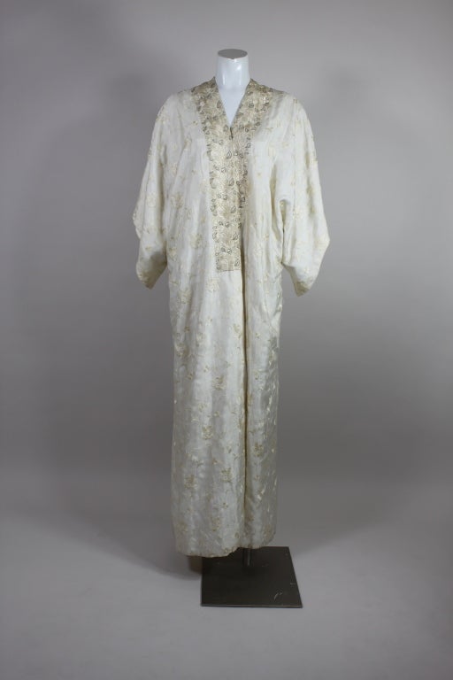 Ce superbe caftan de la maison Babani, datant du début du XXe siècle, est réalisé dans une luxueuse soie ivoire entièrement brodée à la main de vignes florales en volutes. Babani était une maison de couture française connue pour ses importations