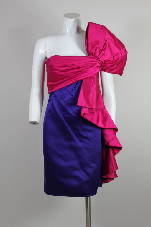 Fabulous party dress from Bill Blass is made from sumptuous jewel-toned silk satin in shades of amethyst and fuchsia. Bodice has a wraparound panel that has a hidden front fastening. A burst of pleated satin decorates the shoulder and cascades down