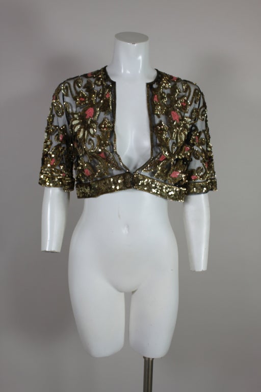 This fabulous, Great Gatsby-era tulle jacket is embellished with shimmering metallic gold sequins. Scrolling, gilded embroidered flowers are accented by clusters of coral and cream sequined petals. Sleeves hit just at the elbow and are banded with a
