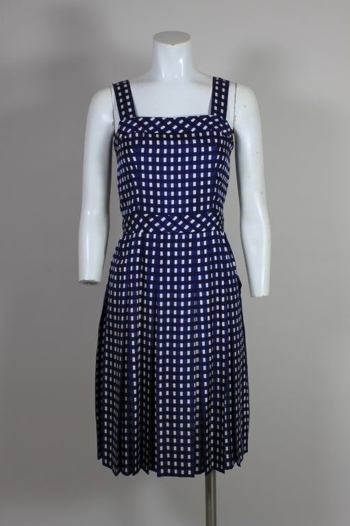 Lovely ensemble from French design house Patou features a sweet silk twill dress with a navy gingham print and a matching jacket. The dress has a flirty skirt with crisp box pleats. The collarless jacket  has an elegant boat-neck and fastens with
