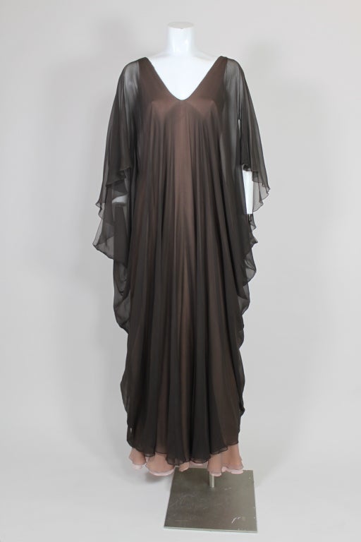 This gorgeous 1970's caftan from George Stavropoulos is made from layers of diaphanous silk chiffon in shades ranging from rich chocolate brown to pale mauve. Caftan has a low v-neck and draped batwing sleeves. Fastens in the back with a zipper.