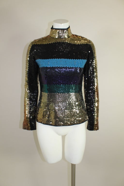 This gorgeous blouse from iconic French designer Pierre Cardin is embroidered all over with metallic sequins. Bold, color-block panels are done in luxe gold, jet black, opaque sky blue, violet, emerald and gunmetal. Blouse has an elegant turtleneck