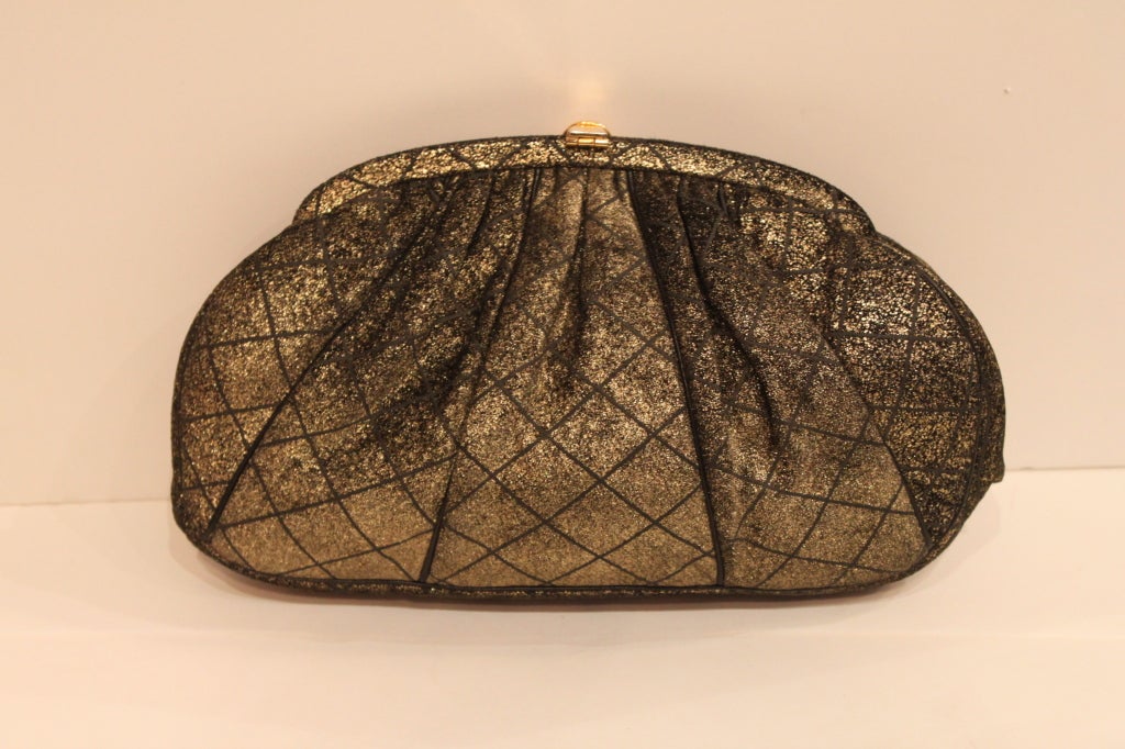 This lovely evening bag from accessories guru Judith Leiber is made from suede brushed with metallic gold pigment. The bag is softly pleated and fastens with a gold infinity clasp decked with jet black cabachons.