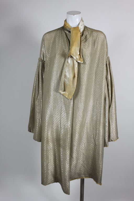 Fantastic, shimmering silk lamé coat is done in a pale metallic gold lined in champagne silk velvet. Billowing sleeves are split from the wrist to the upper arm, and are sewn to the body of the jacket with delicate hand pleats.  Neckline has a