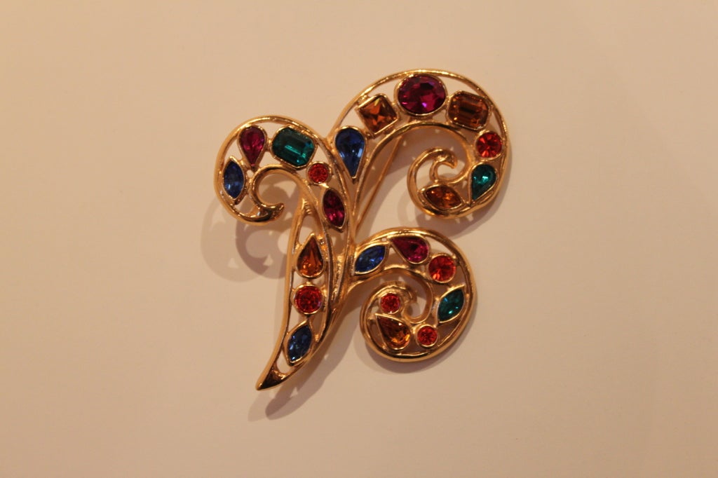Gilt fleur-de-lis brooch from Yves Saint Laurent is decked with geometric, faceted glass jewels in bold shades of fuchsia, topaz, sapphire and emerald. 
