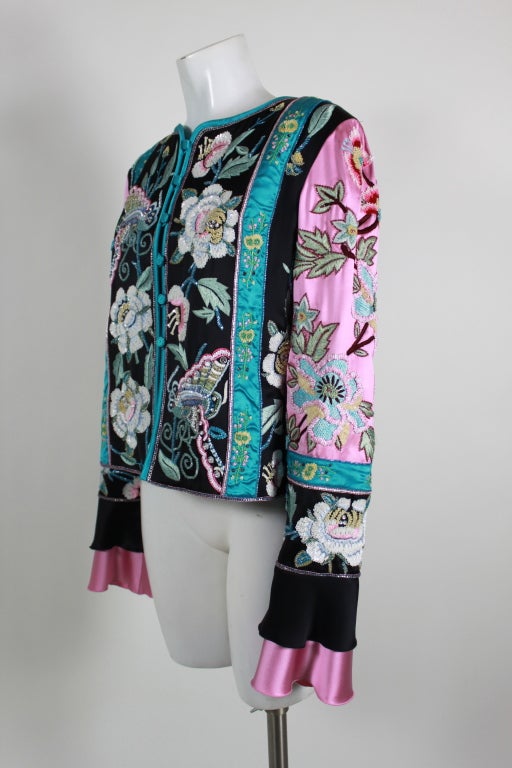 This ornately embellished silk evening jacket from Valentino is made from color-blocked satin in rose pink, black and turquoise. Gorgeous blossoms and butterflies are embroidered along the panels, accented by densely sewn micro sequins and glass