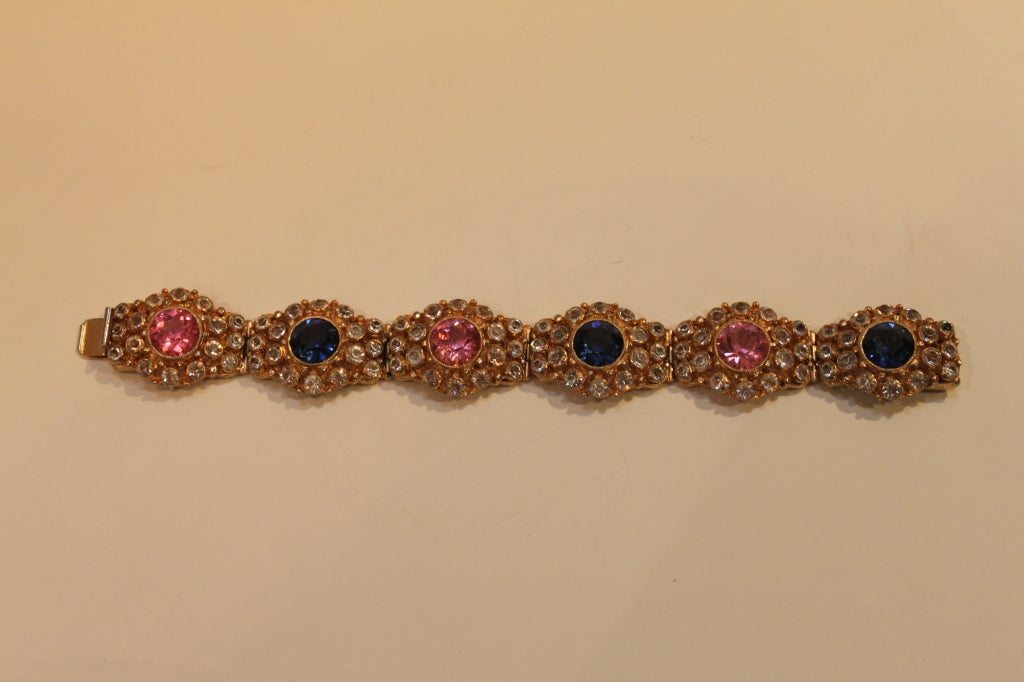 A gorgeous bracelet from French-American costume jewelry house, Hobé, this piece absolutely dazzles with sparkling French paste stones set in gilt metal links. At the center of each link is a brilliantly faceted crystal in alternating pink and blue,