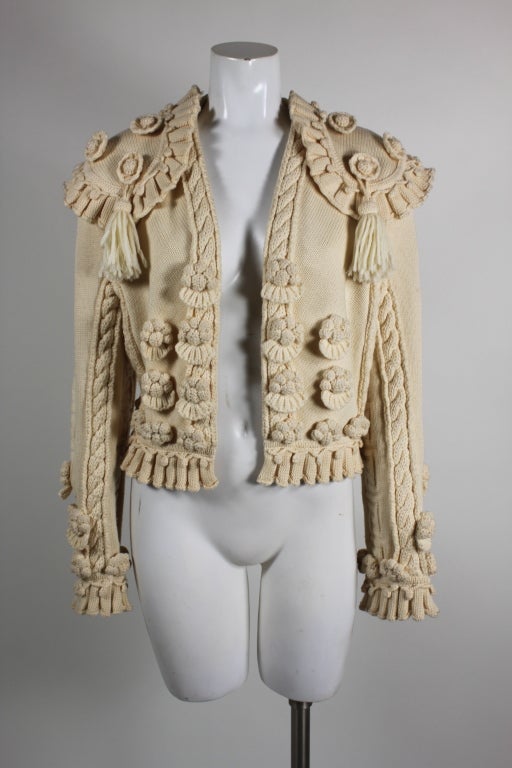 Gorgeous knit wool sweater from Givenchy takes cues from the costume of a Spanish matador, complete with tasseled epaulets and decorative floral medallions. Cream wool is intricately knit into pleated hems and dimensional elements. Givenchy's bold