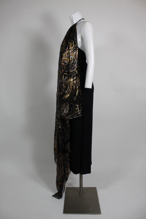 Gorgeous disco-era gown from Sonia Rykiel features a black crepe column dress with a silk chiffon overlay. Overlay is woven with metallic lamé plumes in shades of gold, bronze and pewter. Gown has a dramatic low back and a halter neck. Back zip.