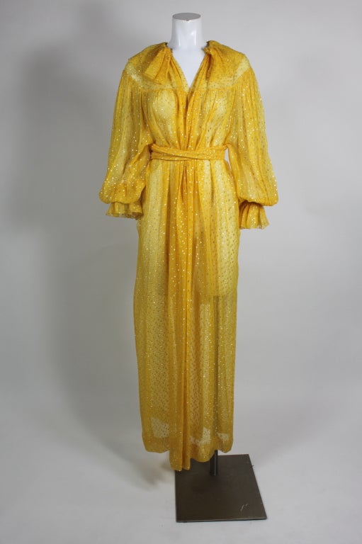 Fantastic 1970s saffron yellow silk chiffon Christian Dior gown is shot with delicate spots of gold lamé. Cut in a bohemian silhouette, the gown has a ruffled collar, blouson sleeves and a lovely waist-cinching tie.