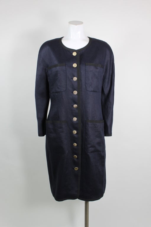 Ultra lightweight and chic, this long-line, linen coat dress from Chanel is almost a deep navy chambray with black trim. Gold quilted buttons are a nod to classic Chanel while also adding to the jacket's modern design. Lined in double-C logo silk.