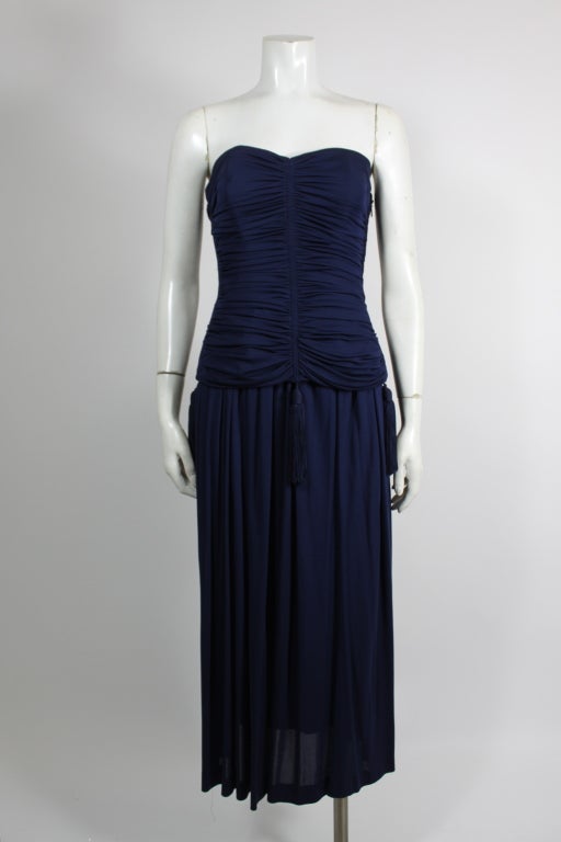 This fabulous ensemble from YSL is done in a rich navy blue. The ruched bustier, accented at the hem with silk tassels, is sexy and modern. Skirt sits at waist.
