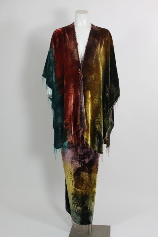A whimsical multi-colored ensemble from Giorgio di Sant'Angelo done in velvet and trimmed with rainbow bead fringe in alternating lengths. The top is a slip-on cape without a closure, and the column skirt zips in the back. 

