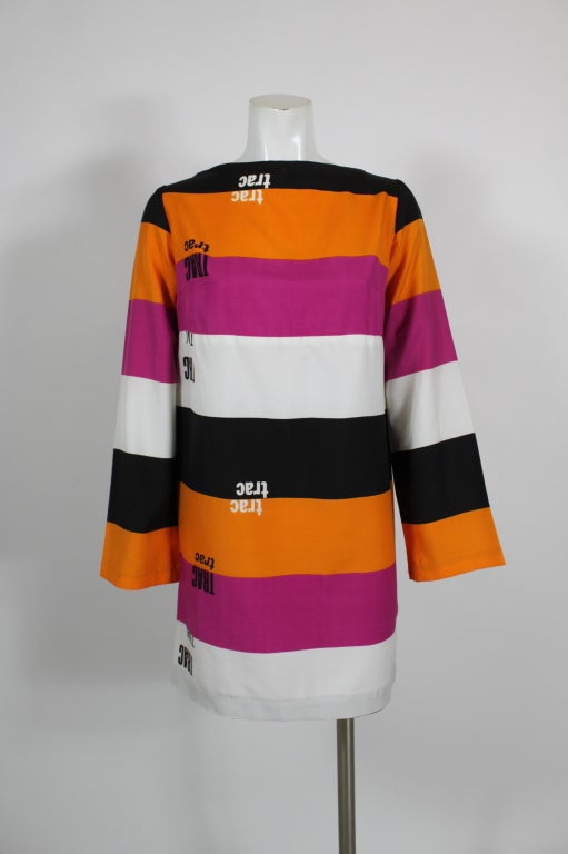 A fabulous, classic mod shift dress from Rudi Gernreich; thick, saturated horizontal stripes in pink, white, orange, and black cover the dress, with graphic type printed throughout. 

Unlined. Zips in back.
