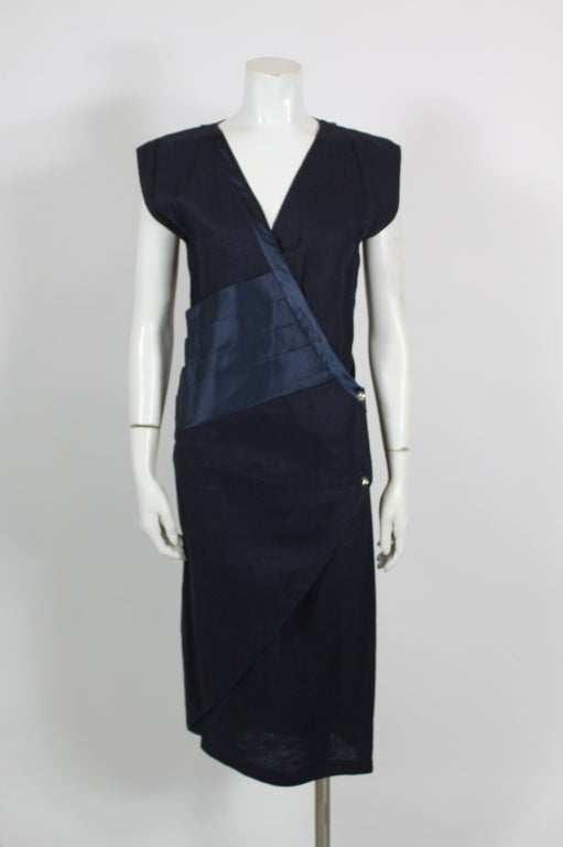 Navy linen wrap dress from Gianna Versace, accented with pleated navy silk detailing at the waist and neckline. Wrap closes with crystal buttons. Hem hits just below the knee.