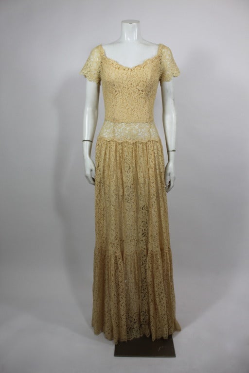 Early 1960s couture gown from Coco Chanel, done in tiered ivory delicate lace. Each layer is finished with a scalloped hem, following the natural design of the lace. The corsetry remains intact. Lace buttons over zipper to conceal its lines.

This