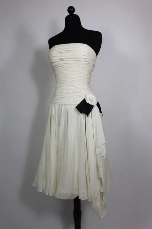This fabulous strapless dress from CHANEL is done in pleated cream chiffon and accented by the iconic Camellia applique at the waist. 

Measurements are as follows:
Bust: 32â??
Waist: 24â??
Hip: free
Length, Center Back to Hem: approximately