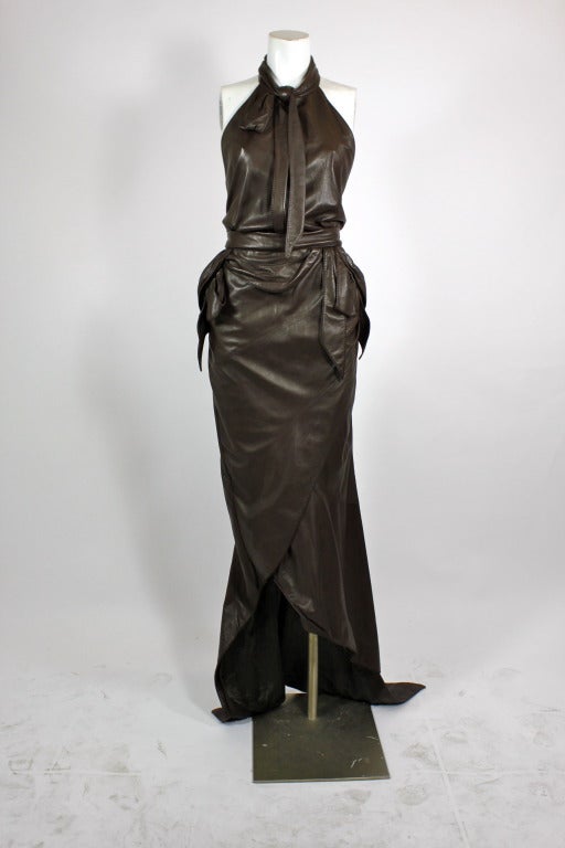 This gorgeous chocolate brown halter gown from Nina Ricci is done in the most supple, luxurious leather. It is accented by various leather knots throughout and is finished with a mermaid hem line. Asymmetrical. Fully lined. 100% lambskin leather. 