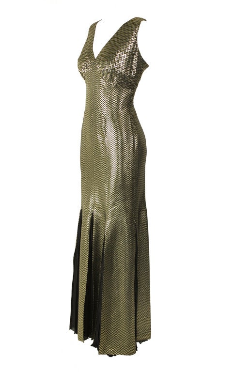 Show-stopping silk lamé gown in black and gold metallic chevron pattern. Kick-pleat godets in black silk chiffon. Shirred bustline. Back zipper closure. 