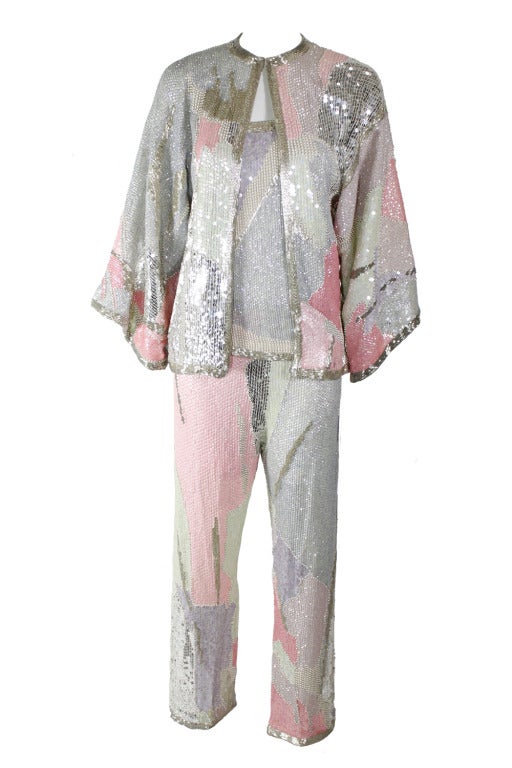 Three-piece set with tank top, jacket and pants by Halston. Patchwork-like design features silver bugle beads; silver, mint, pink and lavender sequins; and cream pearls. Three-quarter bell-sleeves on jacket. One hook and eye closure at collar.
