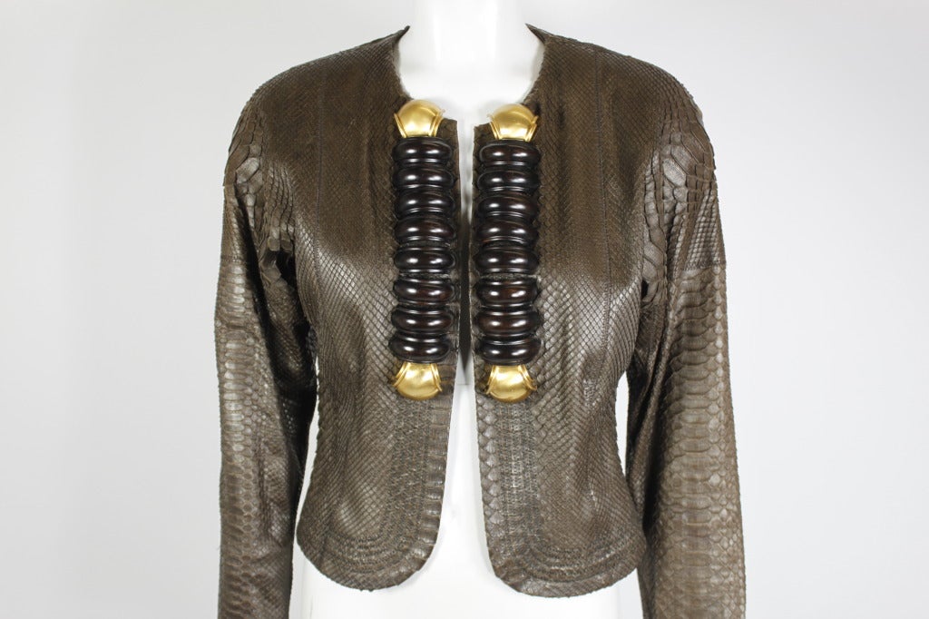 An exquisite snakeskin jacket from Gianfranco Ferre. Jacket is adorned with large wood appliqués and gold-tone pieces, which are affixed with studs through the material. Fully lined. Zippers at wrists.
