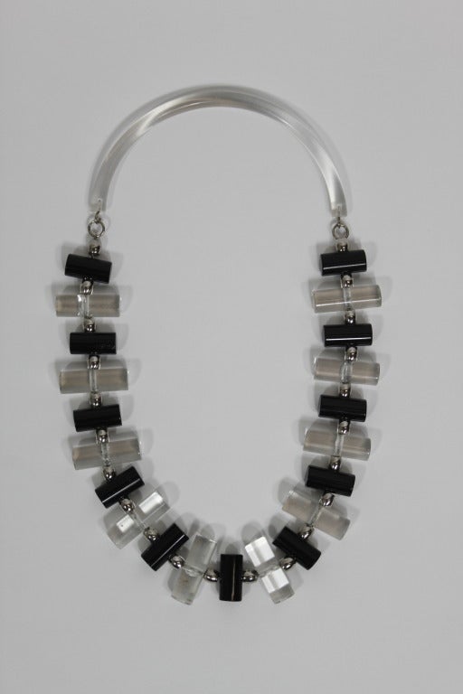 A modernist design necklace from the 1980s, done with structured lucite pieces alternating in black and clear. Closure is a metal hook attached to structured lucite that fits comfortably around the neck.