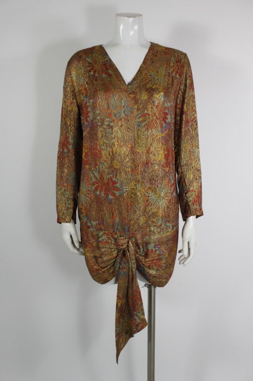 An absolutely gorgeous example of luxurious 1920s floral lamé. The floral patterns almost resembles delicate starbursts, while the lamé threads in swirling patterns throughout. The tunic is dimensional and lovely. Slip-on style: no closure.
