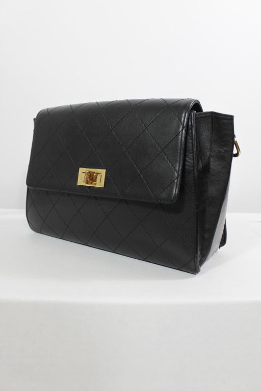 A lovely, classic black leather quilt-stitched shoulder bag from Chanel. Bag is structured and has gold-tone toggle closure with Chanel stamp. Adjustable shoulder strap. Pocket at back and inside zip pocket. Strap length is adjustable between 18-20