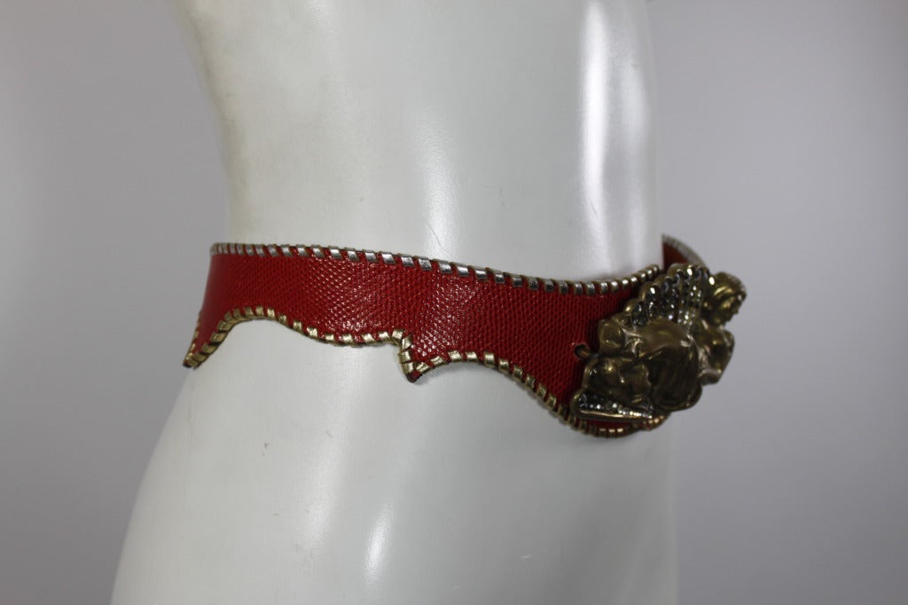 A stunning brass belt buckle from Cesar Ugarte, made in Gstaad. The mermaid-esque goddess is lounging against a seashell motif, embellished with glittering rhinestones. The buckle has two reptile leather belt straps to choose from: a red textured