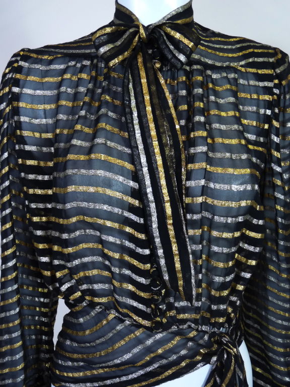 Absolutely stunning sheer  black silk and lamé blouse from the 1930's. Tie-neck blouse has alternating stripes of gold and silver lamé running throughout. Fabric is gathered at the yoke and at the waist to give create a blouson effect. Asymmetrical