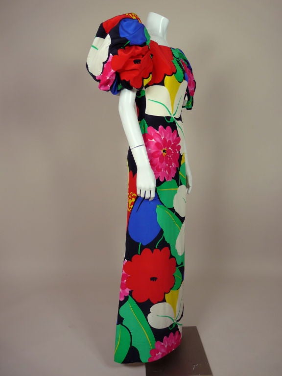 Cheery, bold floral print silk gown from Arnold Scaasi features statement making puff sleeves that are lined in tulle and gathered from shoulder and sleeve hem for extra volume. Gown is fitted at waist and flares at hem for a slight a-line. Zip