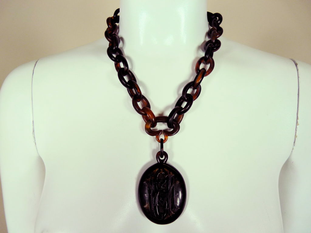 Victorian tortoise shell chain link mourning necklace with large oval shaped monogram locket-style pendant. High relief monogram detail is done in carved scrolling script. Hammered oxidized silver hook and loop closure.